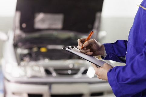Fotografía de un taller de coche, con un mecánico revisando un coche.