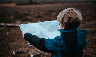 Viajar con niños mirando un mapa, en el campo