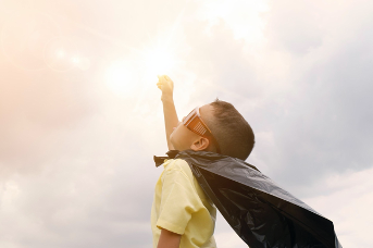 Niño vestido de superhéroe, apuntando al cielo con su puno.
Como viajar con niños divirtiéndose.