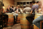 Fotografía en el interior de un restaurante/taberna, con gente tomando una cerveza/vino, en mesas en forma de barril. Muy típico!