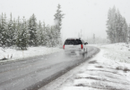 Fotografía de un coche en la carretera, en invierno con nieve en los lados de la carretera.