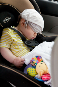 Un bebé dormido en su sillita del coche, con su peluche.
