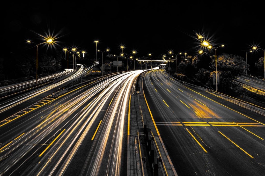 Fotografía de una carretera iluminada de noche por las luces de los coches con velocidad.